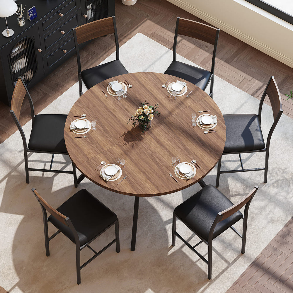 Round wooden dining table with black chairs in a modern kitchen.